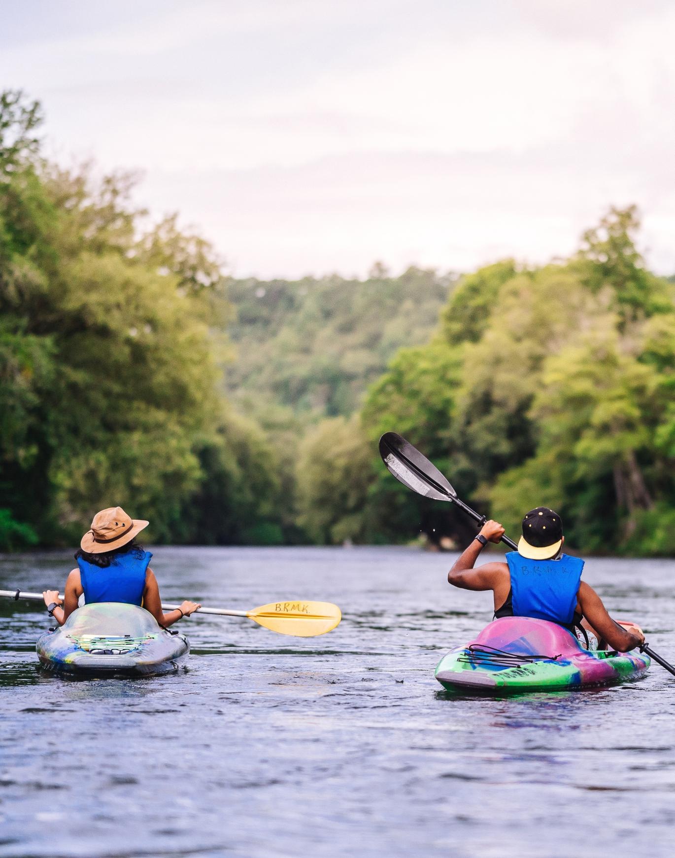 a couple of people paddling kayaks on a lake